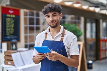 Young arab man waiter using touchpad working at restaurant