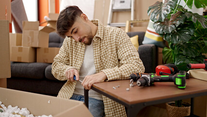 Young arab man repairing table using screwdriver at new home