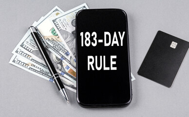 Credit card and text 183-DAY RULE on smartphone with dollars and pen. Business concept