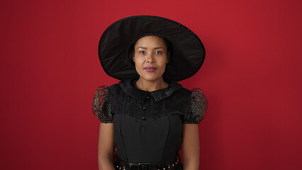 African american woman wearing witch costume having halloween party over isolated red background