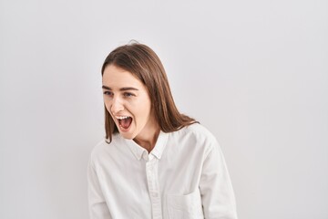 Fototapeta premium Young caucasian woman standing over isolated background angry and mad screaming frustrated and furious, shouting with anger. rage and aggressive concept.