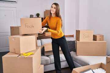 Young caucasian woman smiling confident holding fragile package at new home