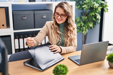 Young woman business worker holding document on folder at office