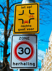 Nederlands road sign with speed limit zone and pass priority for bicycles. Translation - zone repeat and look out, right goes first