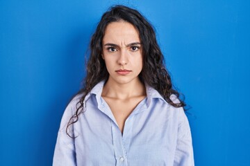 Fototapeta premium Young brunette woman standing over blue background skeptic and nervous, frowning upset because of problem. negative person.