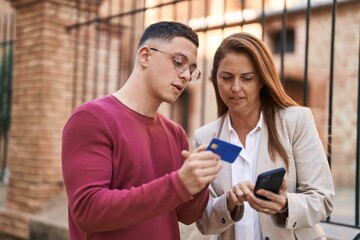 Man and woman mother and son using smartphone and credit card at street