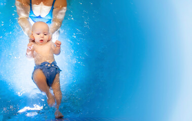 Adorable baby girl enjoying swimming in a pool with her mother early development class for infants teaching children to swim and dive. Swimming instructor doing exercises with a small child in the