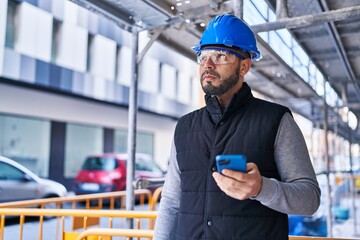 Young latin man architect using smartphone at street