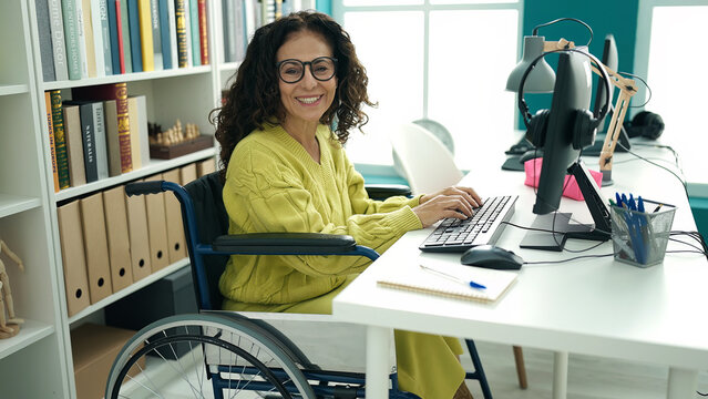 Middle age hispanic woman teacher using computer sitting on wheelchair at library university