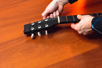 man with guitar, master hand tuner classical guitar strings and pegs tuning, wooden red,pulls...