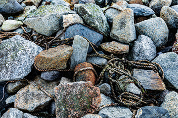 Old rope on the rocks at the sea shore, decorative background or texture