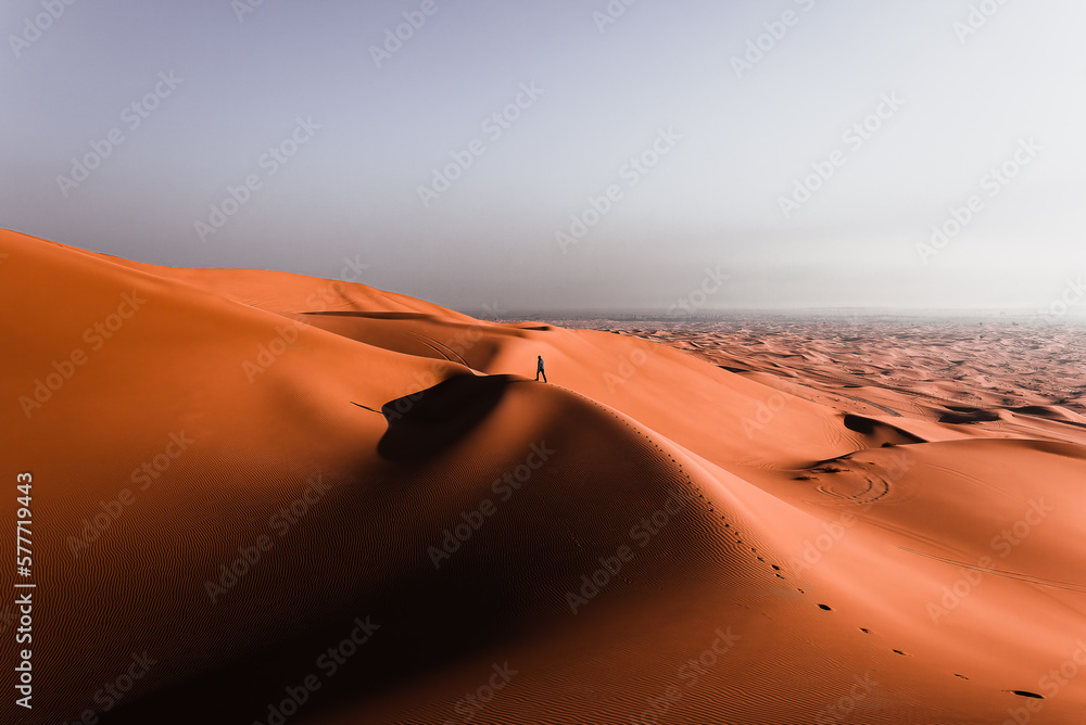 Wall mural man walking on top of a huge desert dune