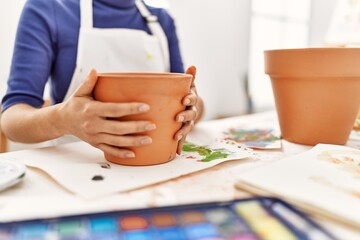 Young latin woman making clay pot at art studio