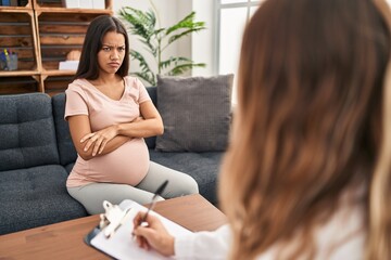 Young pregnant woman at therapy session skeptic and nervous, disapproving expression on face with...