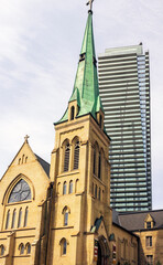 St. Basil's church in Toronto, against the cloudy sky and high-rise modern buildings