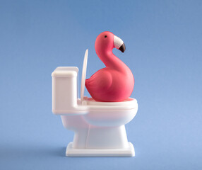 Cute pink flamingo sitting on the toilet on a blue background.