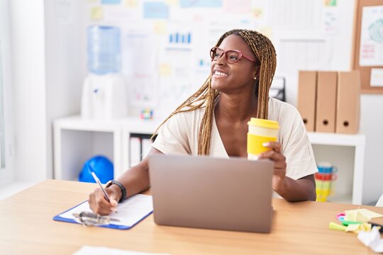 African american woman business worker using laptop writing on document at office
