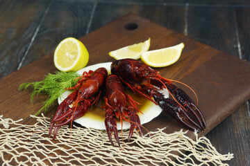 boiled craw fish on kitchen board with net and lemon slices closeup photo