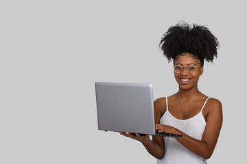 Fototapeta na wymiar woman holding laptop computer typing on keyboard looking at camera, black woman on gray background