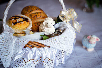 A festive Easter Basket on a holiday table. Traditional Blessing of the Easter Food Baskets. Traditions on Holy Sunday. Horseradish, butter,  bread, buxus, muffin, painted eggs, and Sugar lamb.