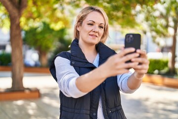 Young blonde woman smiling confident having video call at park