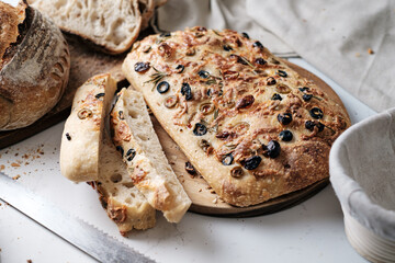 Focaccia with olive tomatoes and rosemary. Homemade Italian Sourdough Bread on white cafe table.
