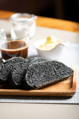 Organic homemade charcoal black bread. set on cafe table with butter and coffee.