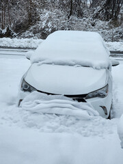 A white car is covered in snow on a street