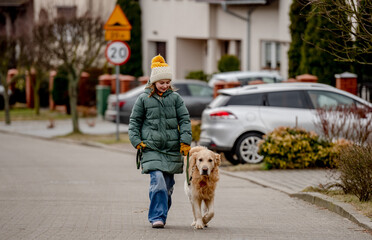 Preteen child girl walking with golden retriever dog