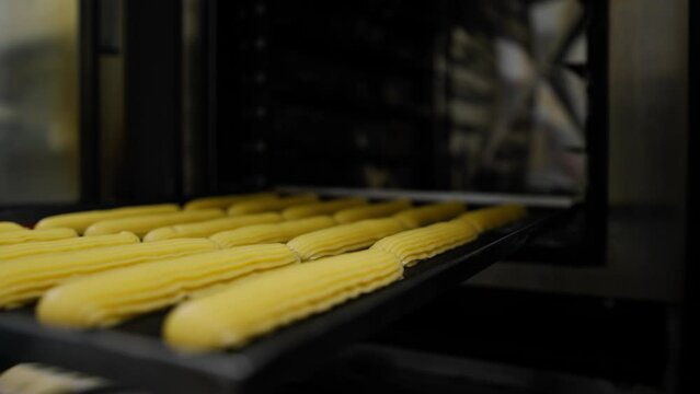Kitchen in a bakery - eclairs on a baking sheet before baking in a bakery