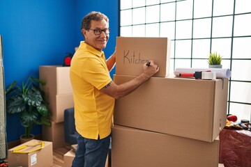 Middle age man smiing confident writing on package at new home