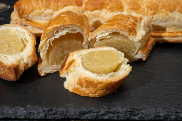 Fresh baked Dutch filled spicy cookies from puff pastry with almonds in autumn colors on dark stone