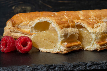 Fresh baked Dutch filled spicy cookies from puff pastry with almonds in autumn colors on dark stone