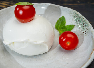 Сheese collection, one big ball on soft white italian mozzarella bufala cheese with red tomato and green basil leaves