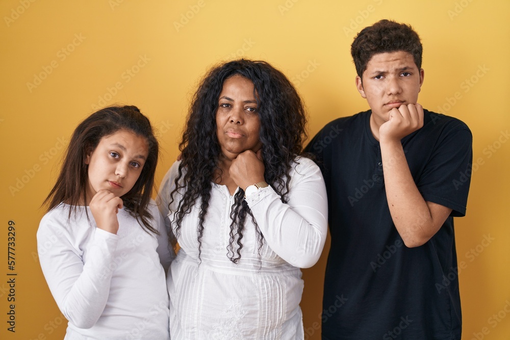 Sticker Family of mother, daughter and son standing over yellow background with hand on chin thinking about question, pensive expression. smiling with thoughtful face. doubt concept.