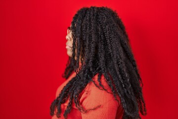 Plus size hispanic woman standing over red background looking to side, relax profile pose with natural face and confident smile.