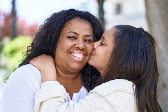 Mother and daughter smiling confident hugging each other and kissing at park