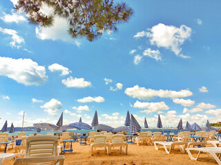 Sun loungers and umbrellas on a sandy beach in sunny weather and white clouds
