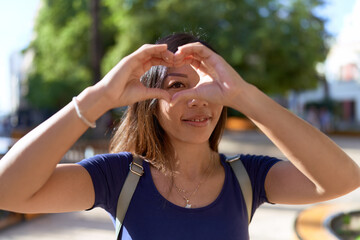 Young asian woman smiling confident doing heart gesture with hands at park