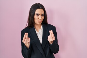 Young brunette woman wearing business style over pink background doing money gesture with hands, asking for salary payment, millionaire business