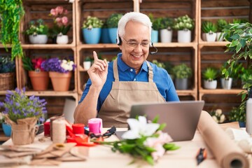 Middle age man with grey hair working at florist shop doing video call smiling happy pointing with...
