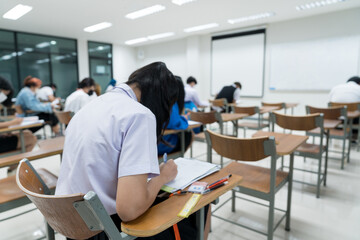 Young teen students taking notes while listening to the lecture in the classroom