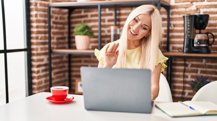 Fototapeta na wymiar Caucasian woman doing video call with laptop looking positive and happy standing and smiling with a confident smile showing teeth