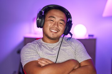 Chinese young man playing video games wearing headphones happy face smiling with crossed arms...