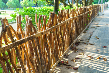 wooden fence made of tree branches in the rays of the sun