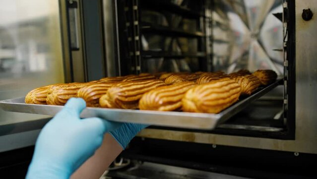 Kitchen in the bakery - ready-made eclairs are taken from the oven