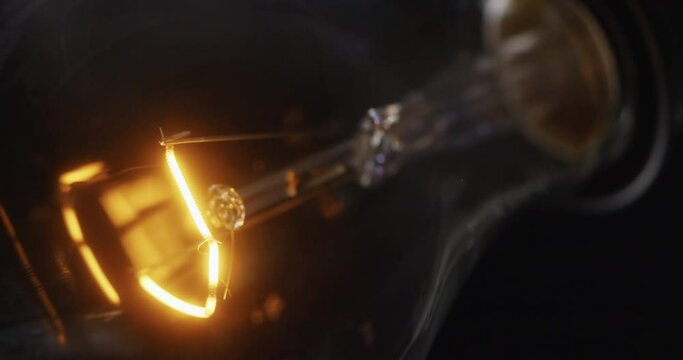 Tungsten light bulb blinking over black background., Follow focus.

