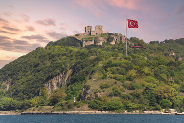 Fototapeta na wymiar Green mountains of Bosphorus Strait at Anadolu Kavagi, with ruins of Yoros Castle, Yoros Kalesi, or Genoese Castle, at the far end, an ancient Byzantine castle,and huge Turkish flag, Istanbul, Turkey