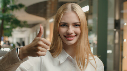 Happy woman 20s businesswoman girl showing thumb up approve gesture yes recommend good business idea agree support excellent result achieve agreement positive lady posing with raised finger in office