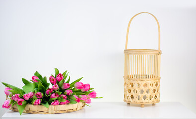 Fototapeta na wymiar vintage handmade wicker rattan tray with spring flowers and decorative lamp isolated on white background. Space for text